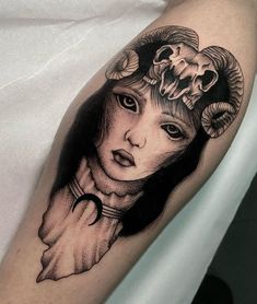 a woman's face with horns and flowers on her head is shown in this black and white tattoo