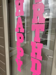 two pink happy birthday letters are on the front door