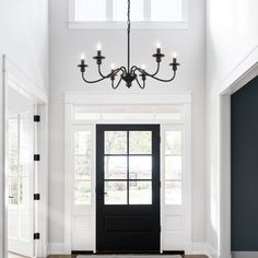 a black and white entryway with a chandelier hanging from the ceiling above it