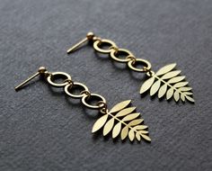 These botanical earrings feature brass fern leaves and are perfect for your Spring or Summer looks! :) * Brass leaf charms, 0.75in (2cm) wide * Brass circle links * Gold plated ball stud posts * Plastic stoppers included Earrings measure 2.125in (53mm) from top to bottom. Les boucles parfaites pour le printemps ou l'été! * Feuilles en laiton, 0,75po (2cm) de large * Cercles en laiton * Barres d'oreilles plaqués or * Stoppers en plastique inclus Hauteur totale d'environ 2,125po (53mm). Nickel Free Gold Botanical Jewelry, Nickel-free Gold Botanical Jewelry, Gold Botanical Dangle Earrings, Nickel-free Botanical Gold Jewelry, Gold Leaf Botanical Jewelry, Botanical Leaf Shaped Gold Jewelry, Botanical Style Gold Leaf Jewelry, Leaf Earrings Gold, Plastic Stoppers