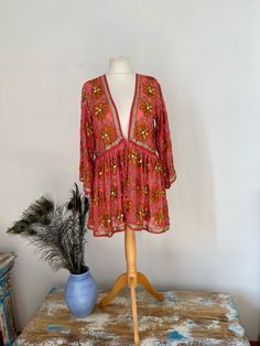 A beautiful embellished kimono jacket/ dress that was made in india. The fabric used is a recycled vintage Indian sari. The base fabric is a pink chiffon crepe with lots of embroidery floral patterns with lots of beads and sequins sewn on. The jacket is open at the front but can be fastened with a broach.  It is very decorative.  As with all recycled vintage fabrics there will be loose threads and missing beads etc, but nothing much.  It measures around the chest 100 cms  The length is from mid Flowy Bohemian V-neck Kimono, Embroidered V-neck Kimono For Spring, Traditional V-neck Sequin Dress, Bollywood Style Sequined V-neck Dress, Bollywood V-neck Sequin Dress, Pink Floral Print Kimono For Beach Cover-up, Bohemian V-neck Tunic With Floral Print, Floral Print V-neck Kaftan For Party, V-neck Floral Print Tunic For Beach Cover-up