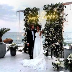 a newly married couple standing in front of an arch with flowers and candles on it