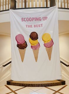 three scoops of ice cream sitting on top of a white banner hanging from the ceiling