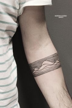 a man's arm with a tattoo on it that has mountains in the background