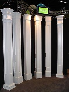 four white pillars are standing in the middle of a room with black walls and carpet