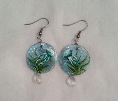 "*Capiz shell  *Stainless steel  *Paint Clip-on or post/stud style available upon request. Beautifully adorable handpainted jellyfish earrings.  Handpainted on 1 inch capiz shells, these are sure to get noticed.   All are approximately 1-1/4\" long with the exception of the one with pearl and chain dangles which measures approximately 2-1/4\" in length.  When light hits the capiz shells, they are irredesent and beautiful, and catch light to reflect colors.  The last three photos show other jelly Jellyfish Earrings, Stainless Steel Paint, Steel Paint, Tree Of Life Jewelry, Capiz Shell, Thanks For The Gift, Stud Style, Unique Gifts For Her, Lovely Jewellery