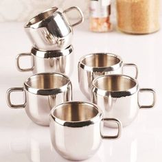 stainless steel pots and pans on a white countertop with spices in the background