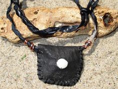 "You will find these type of talisman necklaces and arm bands in many parts of Africa.  They contain blessings inside that offer protection to the wearer. This necklace is crafted entirely from natural dyed black leather, including the cord and has a white shell I found on the beach in Senegal set in the center. The cord is raw twisted black dyed leather.  There are wire copper accents near the pendant. The pendant pouch is 1 5/8\" wide by 1 1/2\" tall and the leather strip is about 26\" long and has a knot and loop closure that allows you to adjust it to any shorter length." Black Shell Necklace, Artisan Black Necklace For Beach, Handmade Black Shell Necklaces, Handmade Black Shell-shaped Jewelry, Bohemian Silver Shell-shaped Necklace, African Bracelets, Talisman Necklace, Small Necklace, Copper Accents