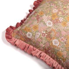 a pillow with pink ruffles and flowers on the front, sitting on a white surface