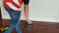 a man in jeans and a red shirt is holding a black bag with white letters on it