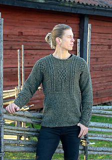 a woman standing in front of a wooden fence wearing a green sweater and black pants