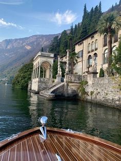 a boat traveling down a river next to a large building with columns on the side