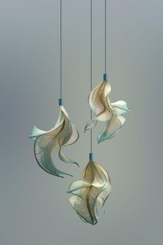 three wind chimes hanging from strings in the shape of flowers with long, wavy tails