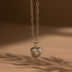 Get ready to fall in love with our Diamond Ribbed Heart Pendant! With its vintage-inspired design and diamond centerpiece, this pendant embodies charm and allure, making it the perfect accessory to showcase your flirtatious style with a hint of elegance. SKU: RR-NR214 Product Details Finish/Material: 18K Gold Over Brass ∙ Rhodium Over Brass Featuring a ~15x15.5mm Heart Charm with embedded ~3mm Diamond CZ Gemstone on a Paper Clip Chain, adjustable from 16 to 18 inches Featured Styles Part of our Diamond Centerpiece, Trombone, Vintage Inspired Design, Chain Link Necklace, Layered Look, Snake Chain, Solid 925 Sterling Silver, Heart Charm, Heart Necklace