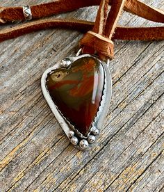 This is a beautiful piece of caressite jasper - a new stone for me. The colors are a deep green with rust and gold running through and is in a heart shape. It's set in sterling silver and hangs on a elk leayher cord in a tobacco color. The pendant is 2 inches by 1 1/4 Inches long with the necklace itself measuring 26 inches and is adjustable with a heavy heart shaped artisan silver ring. This piece is adjustable to make it a choker style necklace.  There is some tiny natural pitting in this stone.  For more artisan jewelry you can re enter my shop here:  https://www.etsy.com/shop/DianesAddiction?ref=si_shop Thanks for stopping by. Please feel free to convo me with questions. Handmade Rustic Agate Jewelry, Adjustable Artisan Moss Agate Jewelry, Adjustable Moss Agate Artisan Jewelry, Rustic Agate Jewelry For Healing, Artisan Jasper Jewelry Gift, Unique Jasper Jewelry Gift, Unique Jasper Jewelry For Gifts, Rustic Agate Jewelry For Gifts, Artisan Brown Agate Jewelry