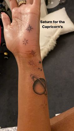 a woman's hand with a saturn tattoo on it and the words saturn for the capricorn's