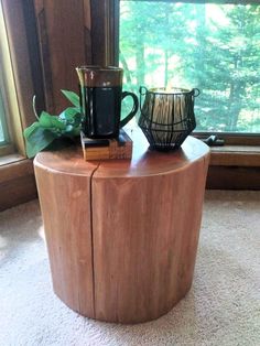 a wooden table with two coffee mugs on top of it next to a window