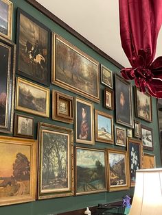 a room with many paintings on the wall and a lampshade in front of it