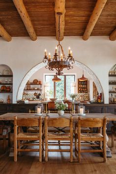 the dining room table is surrounded by wooden chairs and chandelier with candles on it