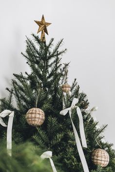 a christmas tree decorated with gold and white baubles, bows and a star ornament