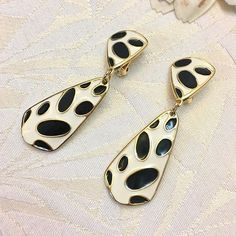 Clip earrings. Material: gold metal. Color: white and black. Width: 1.70 cm (0.67"). Height: 5.50 cm (2.16"). All our objects are vintage and are made Sphinx, a reputable English company that closed its doors in the early 2000s and if they seem new to you it is because they come from a stock of unsold so never worn but nevertheless vintage. Founded in 1948, Sphinx was a British manufacturer, famous for its high quality costume jewellery. In addition to their own collections, often whimsical but always elegant, they have created jewelry for many talented artists and high-end stores, in Europe and the United States (Kenneth Jay Lane, Butler - Wilson, Nina Ricci, Caura, Fried Paris, Saks 5th Ave., Neiman Marcus, Bloomingdales, Mark and Spencer...). Most coins are signed with the name "SPHINX" White Enamel Clip-on Jewelry, Vintage Gold Clip-on Earrings With Black Enamel, Retro White Dangle Earrings, Retro White Dangle Jewelry, Retro White Drop Earrings, Vintage Enamel Earrings For Evening, Vintage Style Enamel Earrings For Evening, Vintage Style Enamel Earrings For Evening Wear, Retro White Clip-on Earrings As Gift