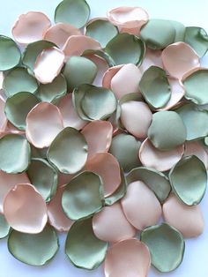 a pile of pink and green petals on a white table top with one flower in the middle