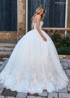 a woman in a white wedding dress standing on a brick walkway next to a fountain