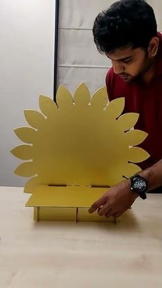 a man is making a paper sunflower out of cardboard