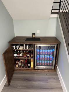 an open refrigerator with drinks and condiments in it next to a stair case