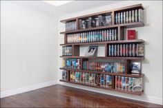 a book shelf filled with lots of books on top of a hard wood floor next to a white wall