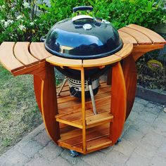 an outdoor bbq grill with wooden shelves on the side