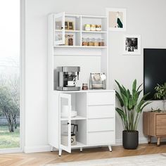 a living room with white furniture and a plant in the corner next to a tv