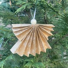 an ornament made out of paper hanging from a christmas tree with pine needles