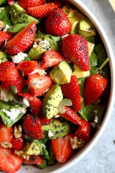 a bowl filled with strawberries, avocado and other fruit