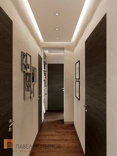 an empty hallway with pictures on the wall and wood flooring, along with white walls