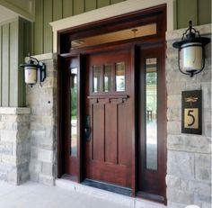 the front door to a home with two lights on each side and an entry way