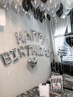 a birthday party with balloons and streamers hanging from the ceiling, along with black and white decor