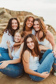 a group of young women sitting on top of each other in front of the ocean