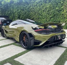 two cars parked next to each other in front of a hedge covered area with grass