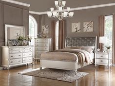 a bedroom scene with focus on the bed, dressers and mirror in the room