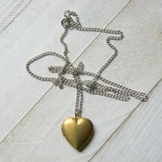 "A vintage brass heart locket hangs from a vintage stainless steel chain to make this simple and easy to wear necklace. The locket measures 7/8\" long and is NOS (new old stock) vintage with varying amounts of patina and scratches on the surface. Choose length at checkout: 16\". 18\". 20\". 22\". 24\". More heart jewelry can be found here: http://etsy.me/1Stzj2o To see more of my handmade jewelry in my Etsy shop, click this link: WearYourWild.etsy.com All jewelry comes nestled in recycled, rusti Vintage Heart Pendant Locket Necklace With Adjustable Chain, Dainty Brass Locket Charm Necklace, Vintage Heart Locket Necklace With Adjustable Chain, Heart-shaped Brass Necklace With Adjustable Chain, Vintage Heart Necklace With Adjustable Chain, Gold Brass Heart Pendant Locket Necklace, Gold Heart Pendant Locket Necklace In Brass, Silver Heart-shaped Brass Necklace, Gold Heart Charm Necklace In Brass