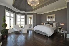 a large bedroom with hardwood floors and gray walls