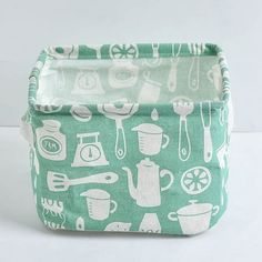 a green and white pot holder with kitchen utensils printed on the front side