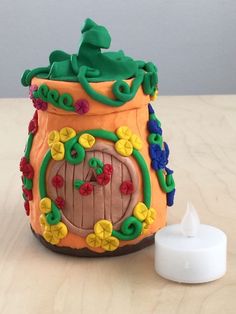 a cake shaped like a pot with a frog on it's lid next to a candle holder