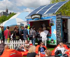 a group of people sitting on the grass in front of a blue and white food truck