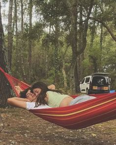 two women are laying in a hammock