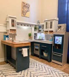 a kitchen with blue and white cabinets, wood counter tops and an area rug on the floor