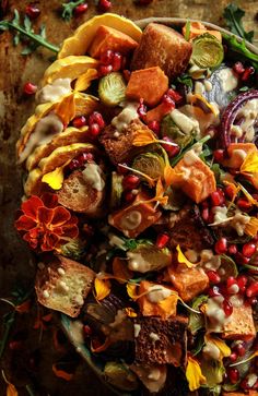 a bowl filled with lots of food on top of a wooden table covered in leaves and flowers