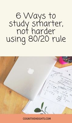 a laptop computer sitting on top of a wooden desk next to a notepad and pen