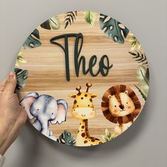 a person holding up a wooden plate with animals and the word's on it